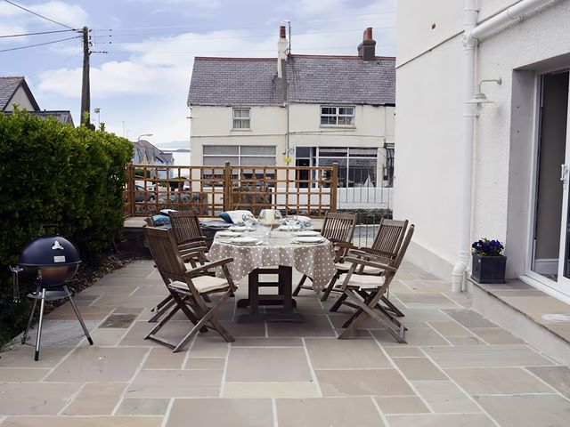 An outdoor patio with a table and chairs at West View Rhosneigr