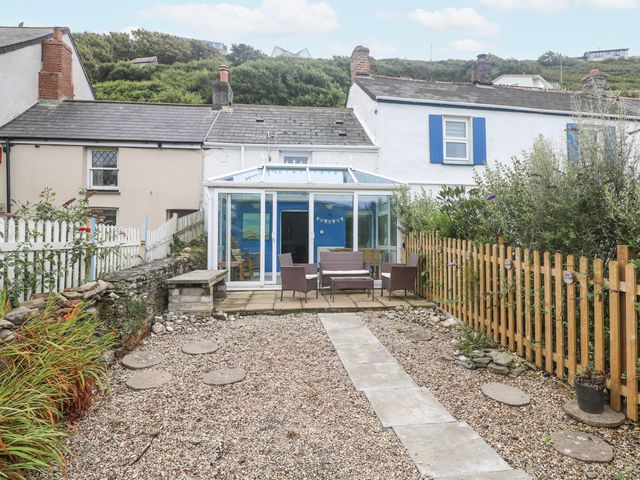 A garden with a conservatory and seating area at Pebble Cottage in Portreath