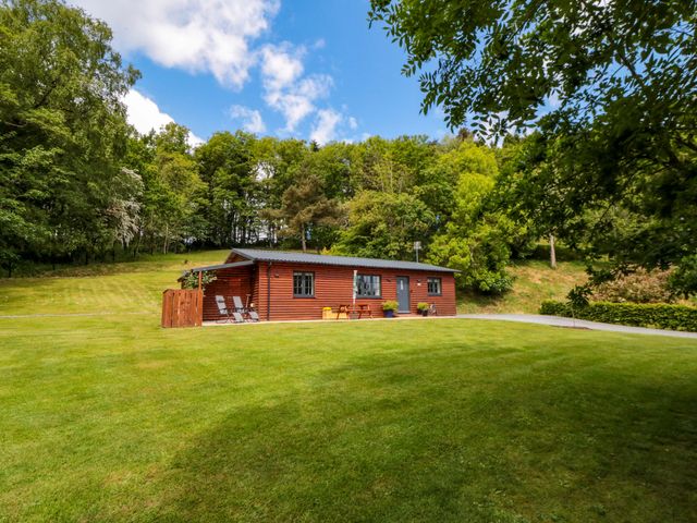 A log cabin with patio furniture and lawn at Ryedale Country Lodges - Hazel Lodge Kirkbymoorside