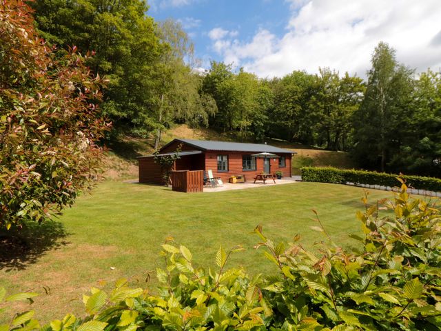 An outdoor garden with a lodge and seating at Ryedale Country Lodges - Willow Lodge in Kirkbymoorside