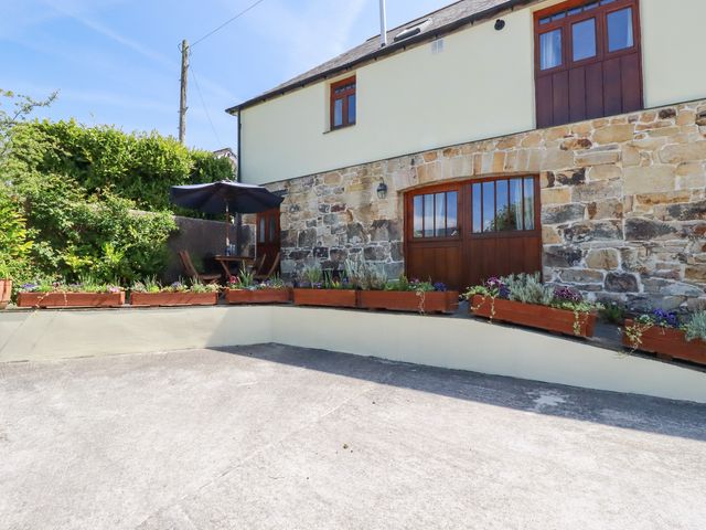 An outdoor patio area with flower boxes stone walls and wooden doors at The Hayloft in Sticker