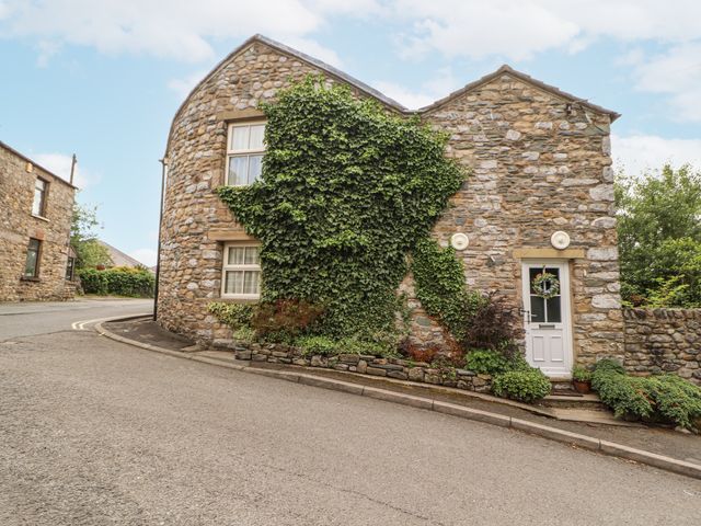 A stone house with ivy and a door at Corner Cottage Ingleton