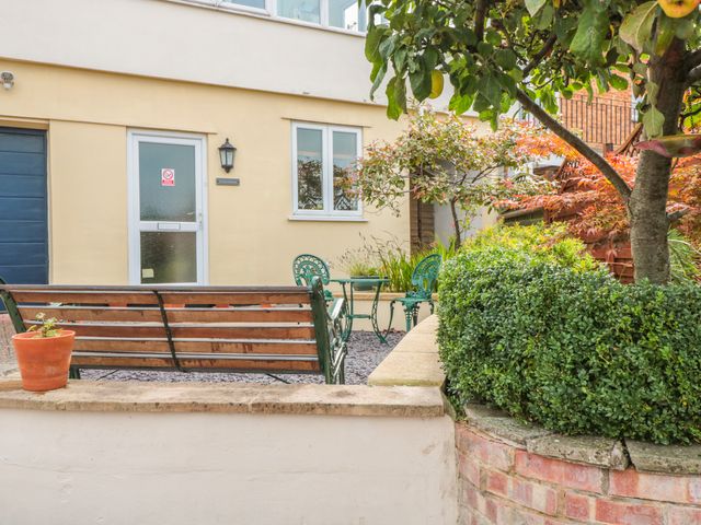 A garden area with a bench, small table and chairs, potted plant, and a tree at Church Road Annexe in Cinderford