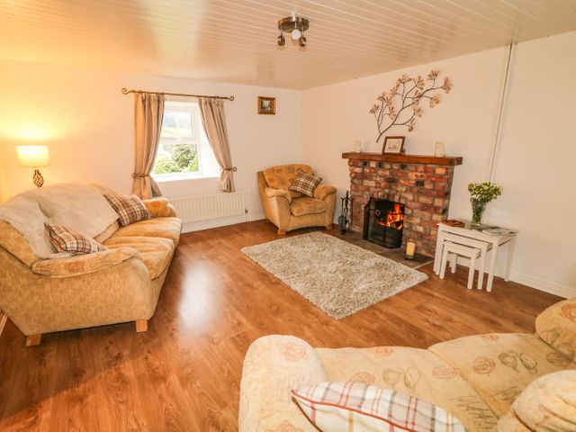 A living room with sofas a rug and a fireplace at Shaws Hill Farmhouse in Kells County Antrim