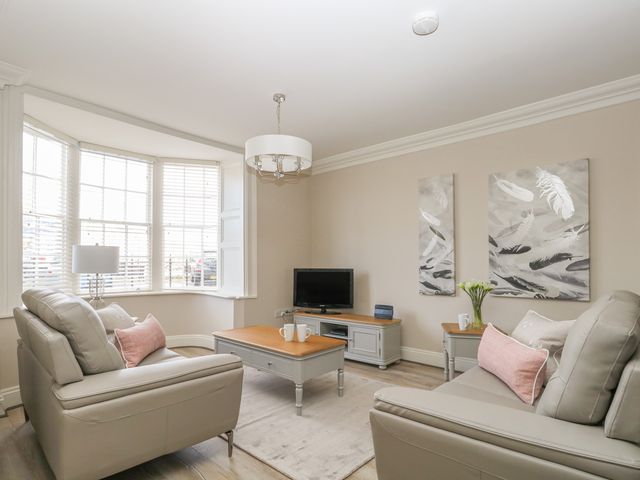 A living room with two sofas a coffee table a TV and paintings on the wall at Harbour Watch 2 in Weymouth