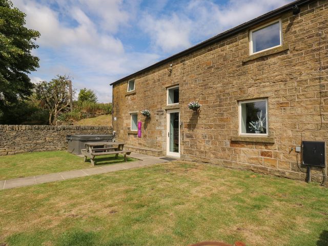 An outdoor area with a stone house and picnic table at Upper House Barn in Delph