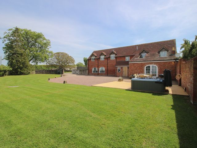 A house with a lawn and hot tub at Hunters Moon in Tenbury Wells