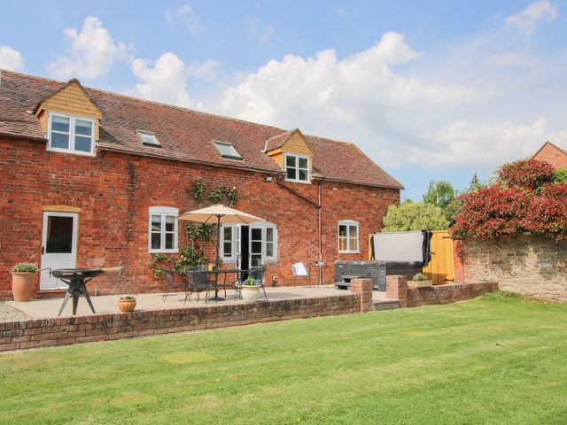 A brick house with a patio table and umbrella in a garden at The Chestnuts in Tenbury Wells