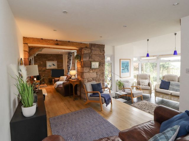 A living room with wooden beams stone wall chairs and sofas at Barn End in Sleagill near Shap