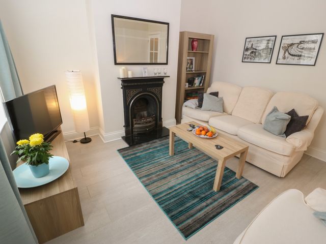 A living room with a beige sofa coffee table and a fireplace at Hazelmere Cottage in Creswell