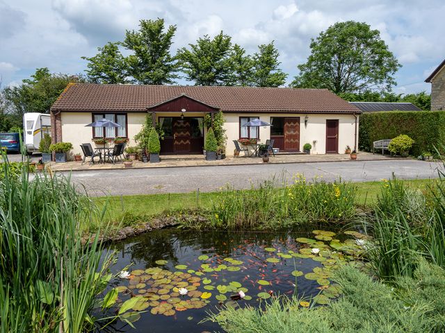 A house with a pond and seating area at Willow Barn Cucklington near Wincanton