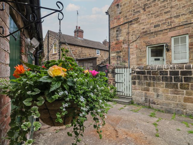An outdoor area with a flower basket and stone walls at Milford Cottage in Milford near Duffield