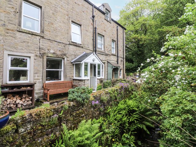 An outdoor area with a house, a bench, and plants at Bridgend Cottage in Eastby near Embsay
