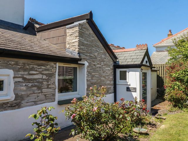 A cottage exterior with flowers and a sign at Cove Cottage in Tintagel