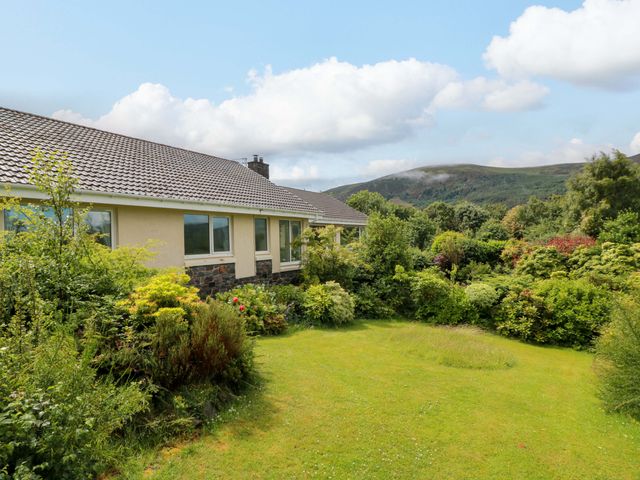 A house with a garden and mountains in the background at Knockendoch in New Abbey