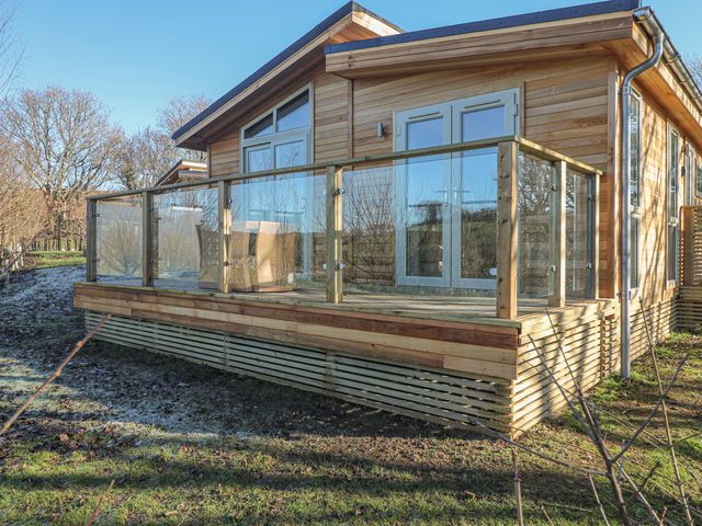 A wooden cabin with glass balcony railing and outdoor furniture in a natural setting at 1 Valley View in Lanreath