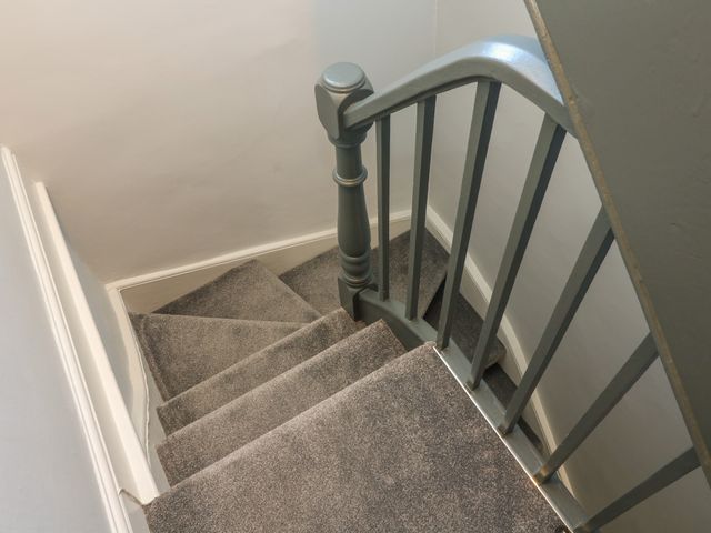 Carpeted staircase with gray painted banister and white walls at Number Thirty-Nine in Ulverston
