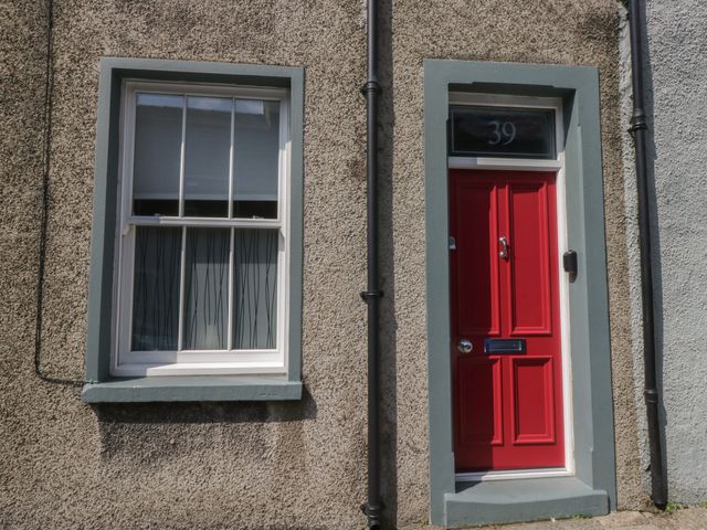 A red door and window on a textured wall at Number Thirty-Nine in Ulverston