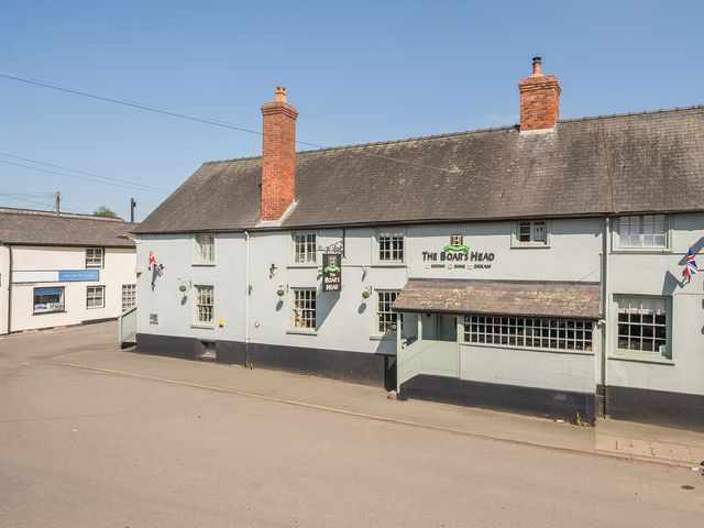 Exterior view of The Boars Head pub with chimneys and Union Jack flags at Bishop's Castle