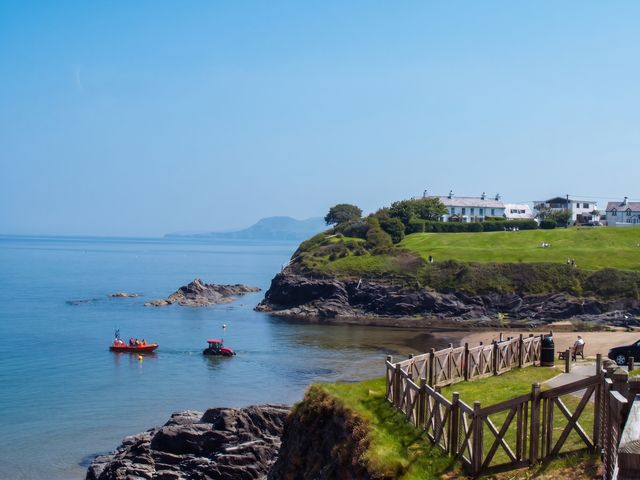 A view of the ocean with boats near a cliff and houses at Beach Retreat in Aberporth