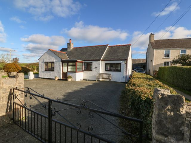 A white detached house with a black iron gate and a driveway at Penllwyn in Llanddona near Beaumaris