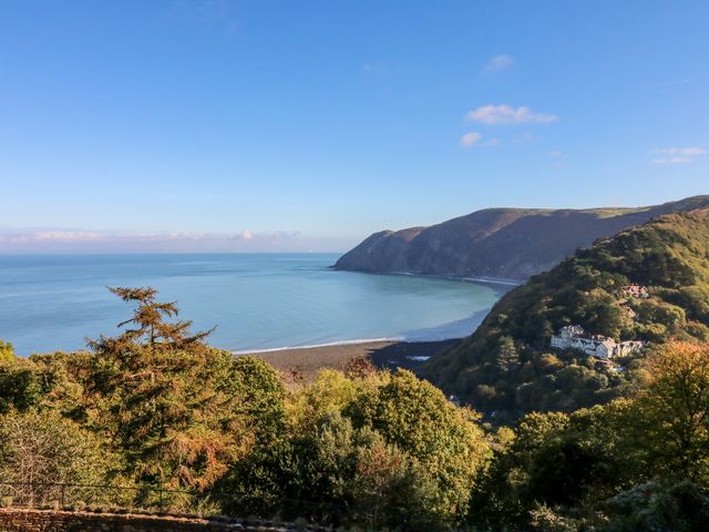 A coastal landscape with a bay surrounded by hills and trees at Blue Bay in Lynton