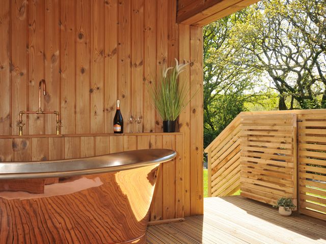 A bathroom with a bathtub and a view outside at The Hideout in Lanreath