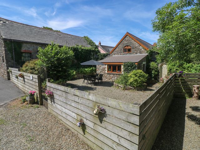 A house with a table and chairs under an umbrella at Barn Court Cottage in Narberth, Pembrokeshire