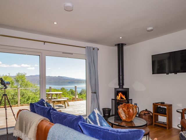 A living room with a fireplace and a tv at The Lookout in Saasaig near Broadford
