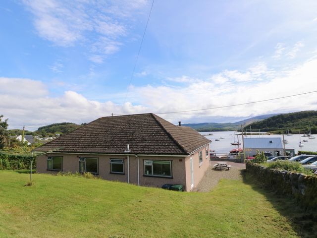 A house with grass and a view of water and boats at Am Bruaich in Tayvallich