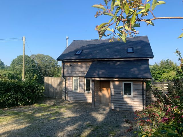 A house with a wooden door and windows at Brynlikky Cottage, Chapel Lawn near Bucknell