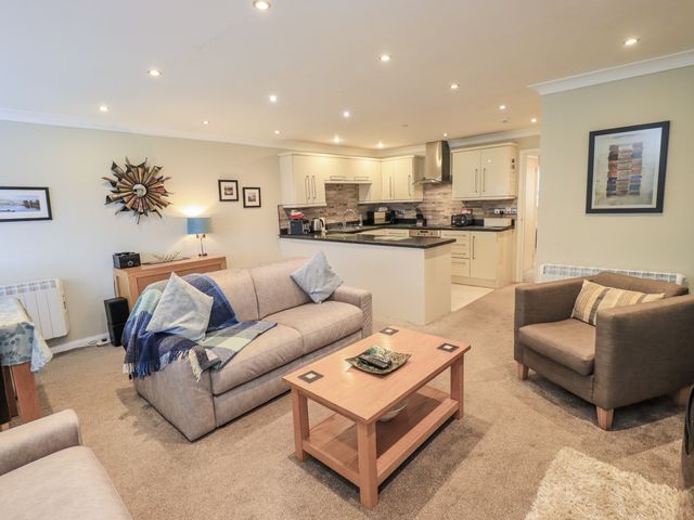 A living room with sofas and a kitchen in Lakeland Loft Windermere