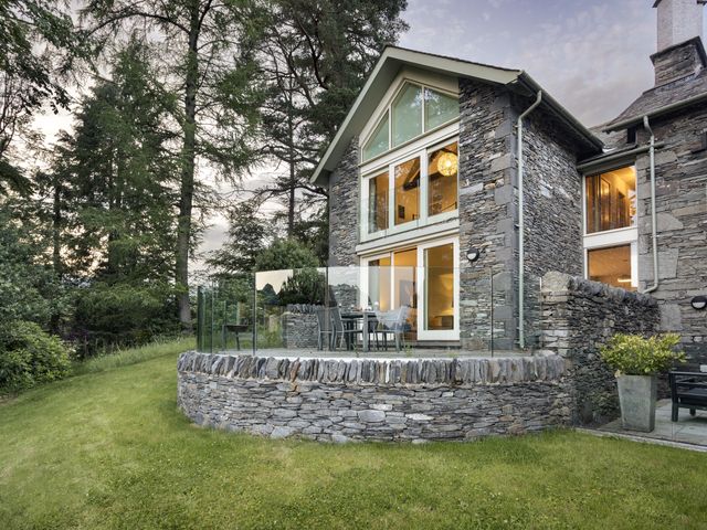 An outdoor area with a stone wall and a glass railing at Take Five in Ambleside