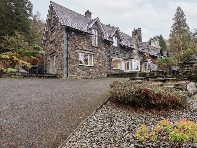 A stone house with a driveway and garden at Fairfield Cottage in Grasmere
