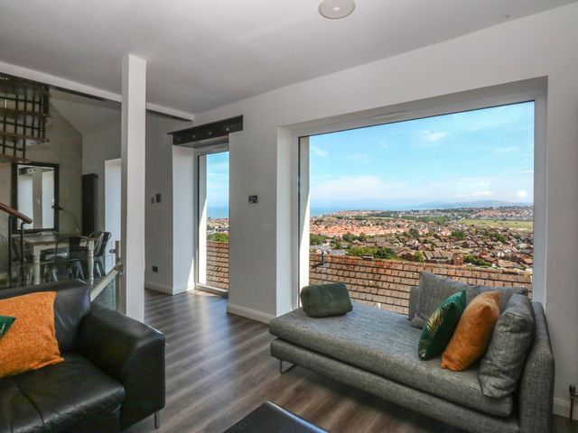 A living room with a sofa and large windows at Sea View in Llandudno