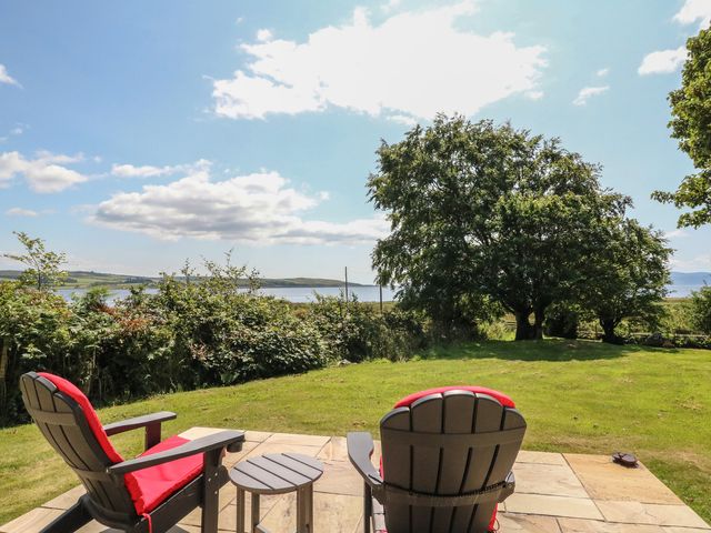 A garden with outdoor seating and a view of water at Ettrick Cottage Rothesay