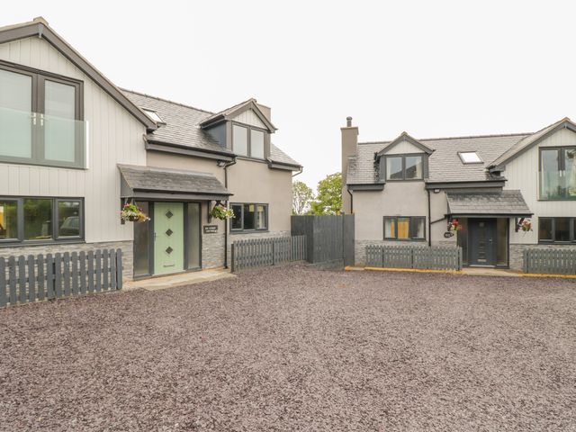 Two modern houses with fenced yards and gravel driveway at Big Azzles in Tyn-y-Gongl near Benllech