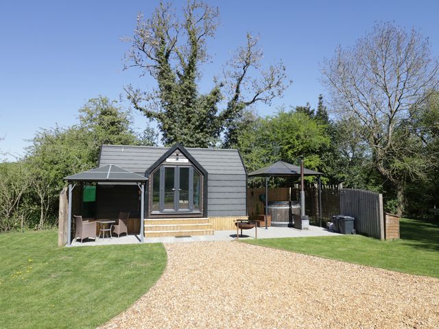 A cabin with outdoor seating and a hot tub at Acorn Lodge At Bridge Lake Farm & Fishery Chacombe