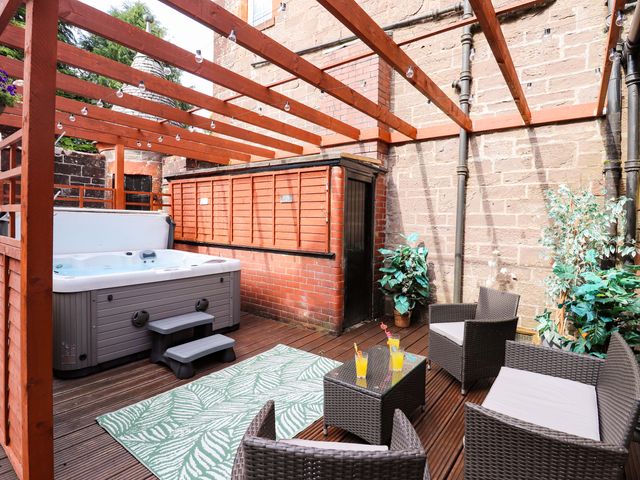 An outdoor seating area with hot tub and table at Rob Roy Apartment in Buchlyvie