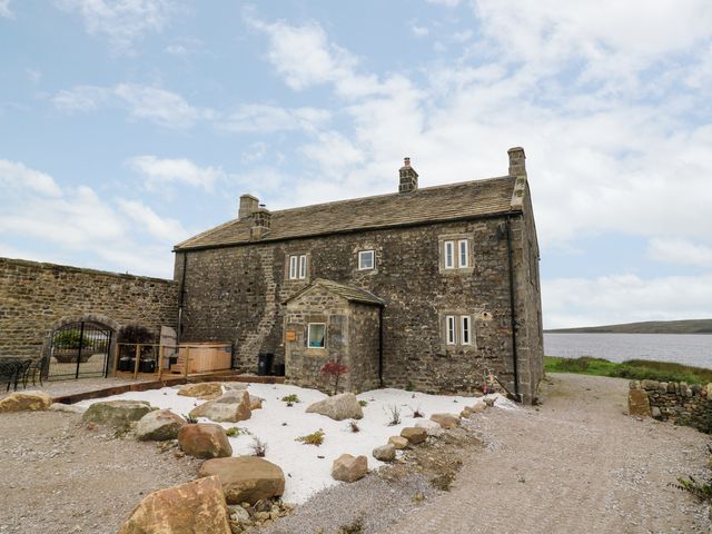 Stone house with small windows and a rock garden outside near a body of water at Skyfell in Grimwith near Appletreewick