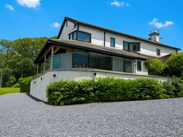 A house with a balcony and gravel driveway at Cleabarrow Cottage Bowness