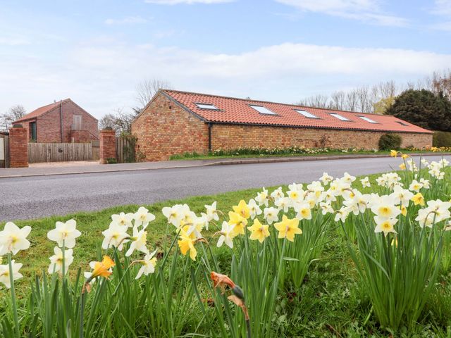 An outdoor view with flowers and a building at Plough Cottage in Little Kelk near Bridlington