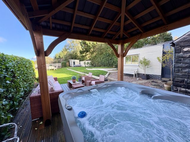 A hot tub with outdoor seating and a lawn at Coupling Cottage in Belper