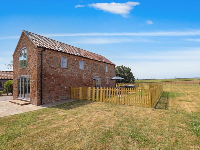 A brick house with a fence and patio in the garden at Acacia Barn Wrangle near Friskney