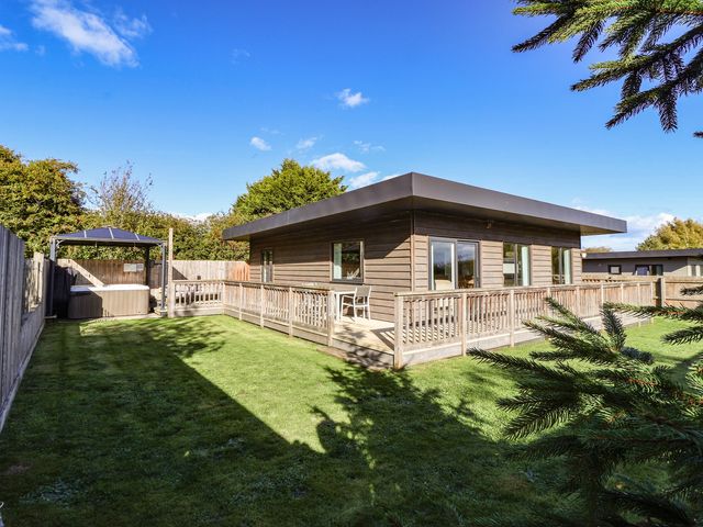 A log cabin with a deck and hot tub in the garden at Bluebell Wood in Brandesburton