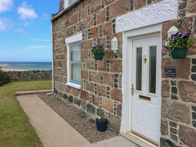 A stone cottage exterior with a white door and window overlooking the sea at Bellas Beach Cottage in St Combs near Fraserburgh