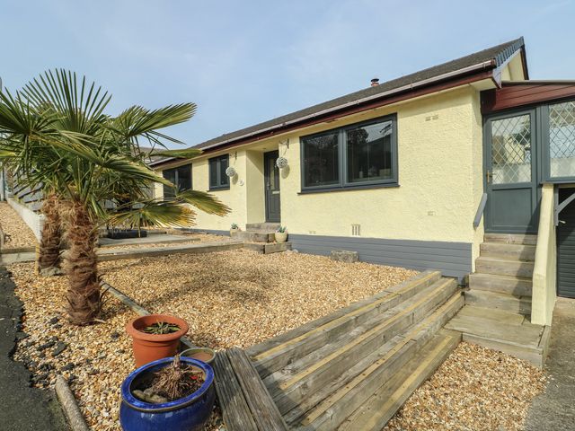 A house with gravel landscaping and palm tree at Daisy Cottage in Benllech