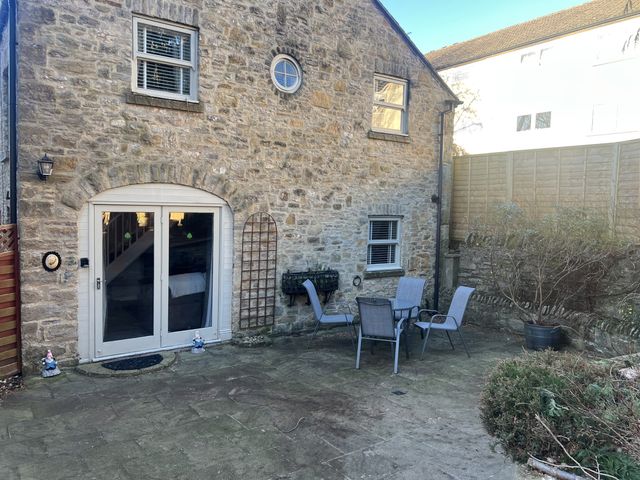 An outdoor area with a stone wall and furniture at Honeysuckle Cottage in Richmond