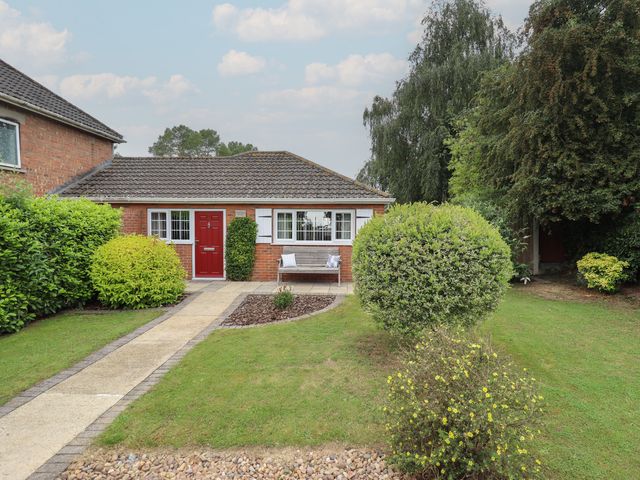 A house with a red front door and garden at Marsh View Cottage in Wainfleet All Saints