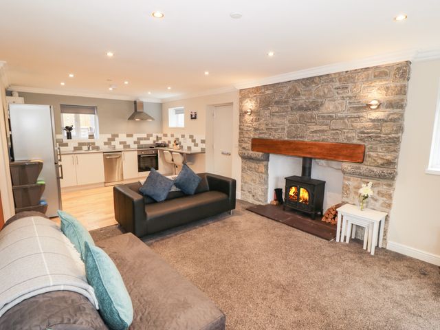 A living room with sofas and a fireplace next to a kitchen with white cabinets at Bryn in Bethesda